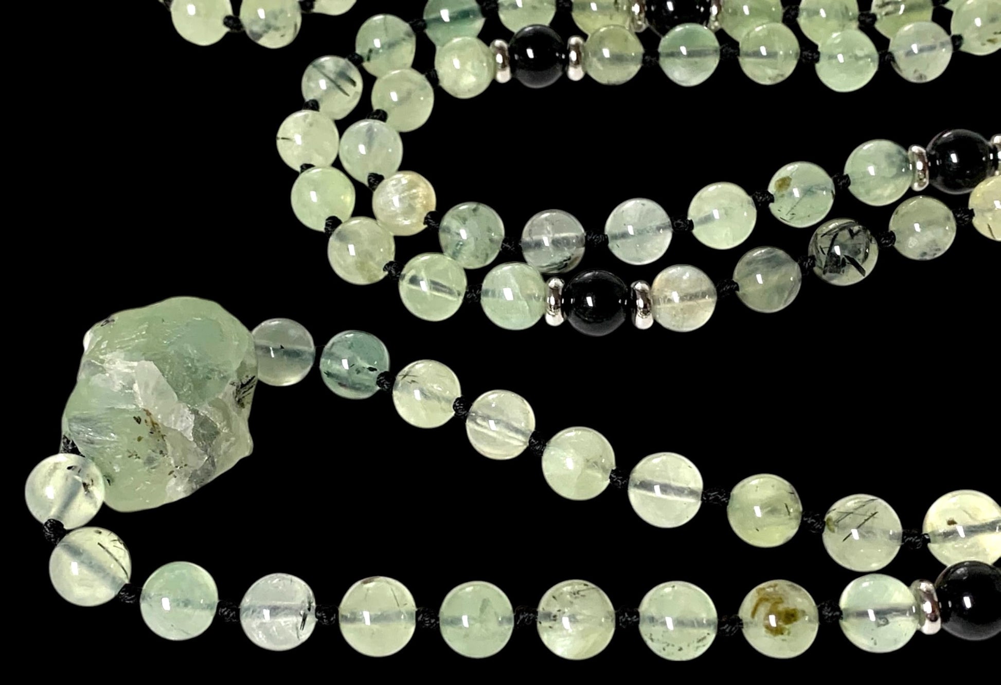 Close-up view of 8mm prehnite gemstone beads showing natural green color variations and hand-knotted construction, Heart Chakra Solar Plexus Chakra healing properties, Collection quality, meditation mala beads, spiritual jewelry detail"