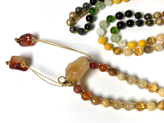 Close-up view of Solar Alchemy Mala beads showing citrine, golden rutilated quartz and fire agate gemstones