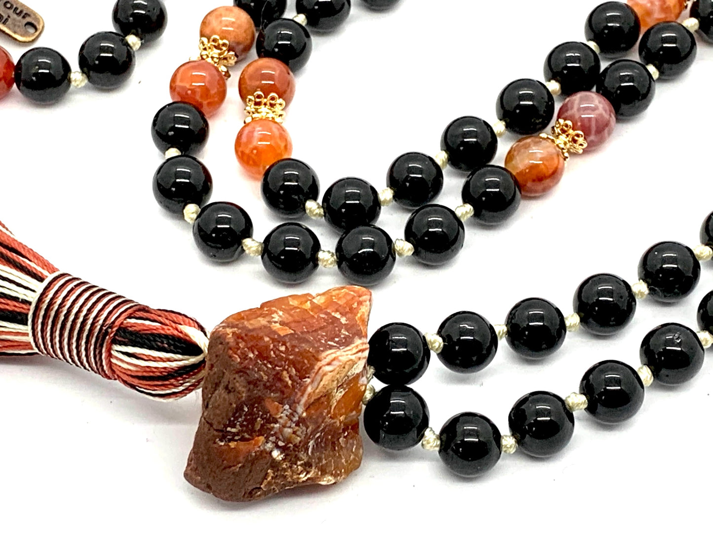 Detail shot of black tourmaline, fire agate and carnelian beads for root and sacral chakra healing